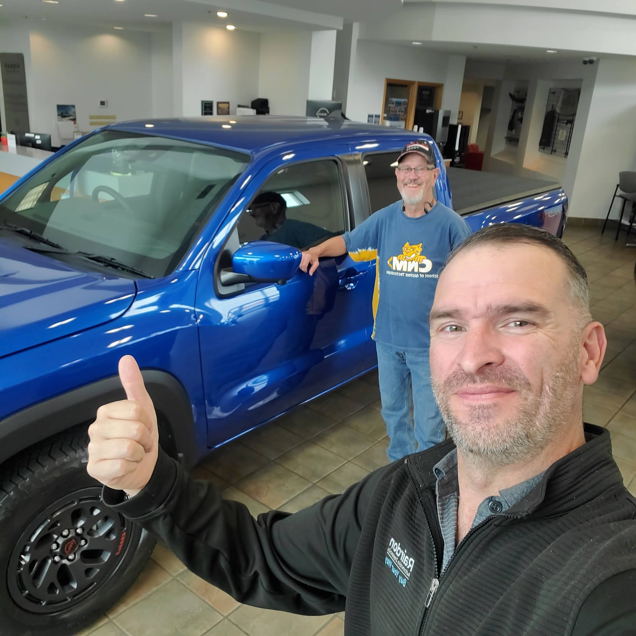 Ian with a happy customer standing next to a vehicle — helping find the perfect car, truck, or commercial vehicle