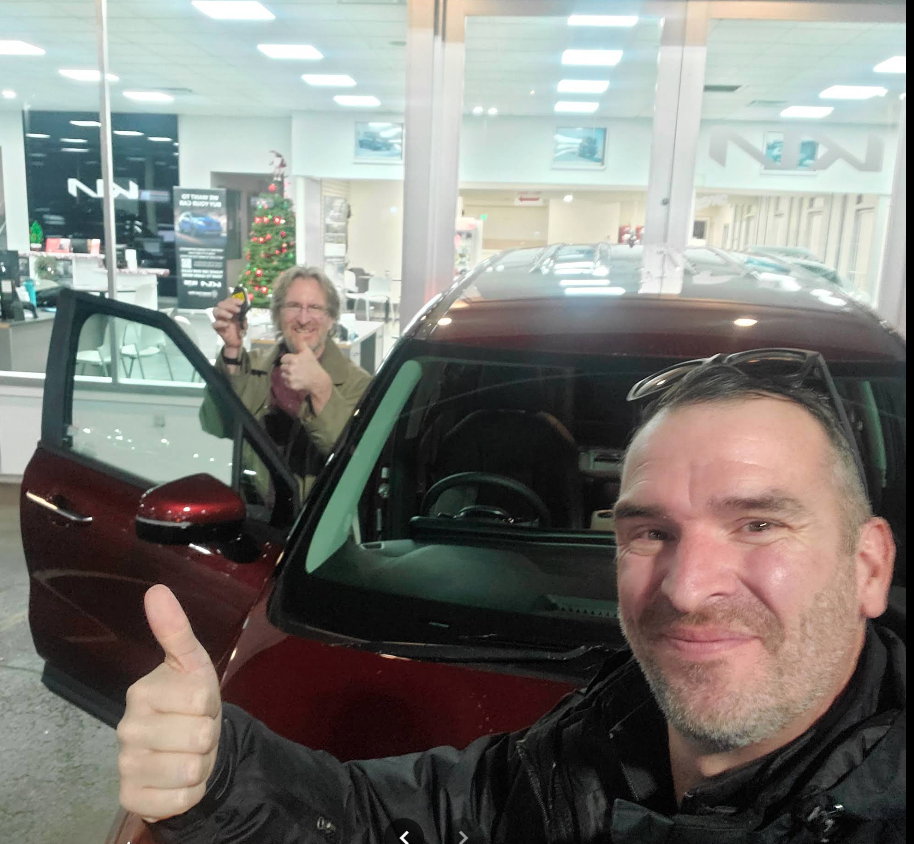 Rachel Goon with Ian next to her new grey KIA — delivery day photo